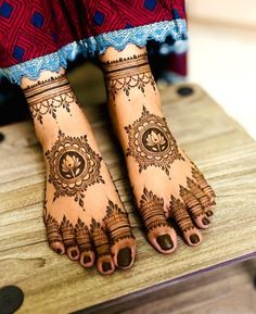 the legs and feet of a woman with henna tattoos on their hands, sitting on a wooden table