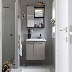 a bathroom with gray walls and white counter tops, along with shelves above the sink