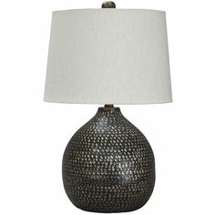 a black and gold vase lamp with a white shade on the top, sitting against a white background