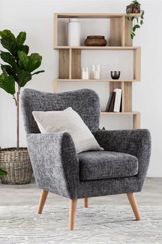 a grey chair sitting in front of a book shelf