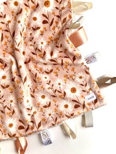 the fabric has flowers on it and is pink with brown trims, along with ribbon ties