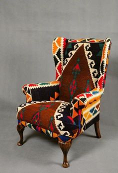 an upholstered chair with multicolored fabric and wooden legs, on a gray background