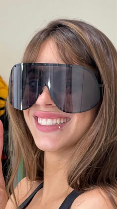 a woman wearing sunglasses and giving the peace sign