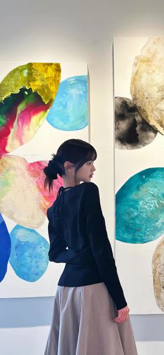 a woman standing in front of two paintings