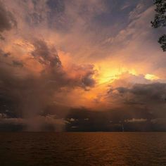 the sun is setting over the water and clouds