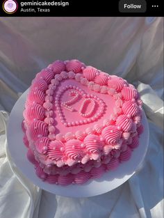 a pink heart shaped cake sitting on top of a white tablecloth covered table cloth