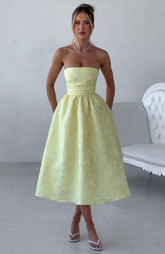 A dress to wear all seasons, Saoirse in Lemon is cut from our prettiest floral jacquard fabric in a midi length with super full skirt lined with tulle for extra volume. This strapless style has boning in the bodice for a cinched waist, with pleating and gathered detailing. The look is complete with lace up back. Wear with a pointed heel and chic hair up.Â     Colour: Lemon.  Floral jacquard fabric.  Fully lined.  Full skirt with tulle for volume.  Pleated bodice.  Boning in bodice.  Gathered det Cute Midi Dresses Classy, Yellow Dresses For Wedding, Formal Casual Outfits Women Dress, Jacquard Midi Dress, Grad Dresses Midi, Two Fabric Dress, Race Day Dress, University Grad Dress, Bridesmaid Dresses Midi Length