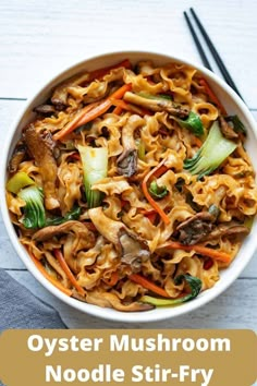 a bowl filled with noodles and vegetables next to chopsticks on a white table