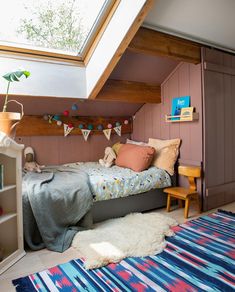 an attic bedroom with a bed, rug and bookshelf on the side wall