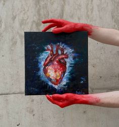 two hands holding up a painting of a heart