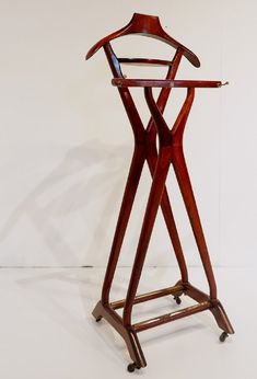 a wooden garment rack with two hangers on it's sides and one standing upright