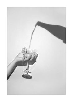 a person holding a wine glass in their hand with the shadow of a woman's arm