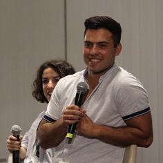 a man holding a microphone while standing next to a woman