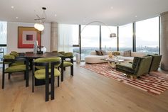 a living room filled with lots of furniture and large windows overlooking the cityscape