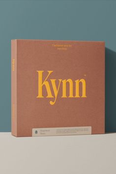 Terracotta coloured product box packaging with bright embossed yellow Kynn logo front and centre. The box sits against a blue teal background. Product Box, Good Color Combinations, Materials And Textures, Window Design, Functional Design, Box Design, Shapewear