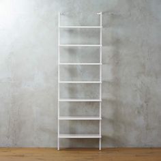 a tall white shelf sitting on top of a hard wood floor next to a wall