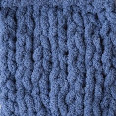 a blue crocheted blanket is laying on the floor