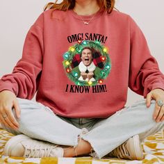 a woman sitting on the floor with her mouth open wearing a sweatshirt that says, once santa i know him