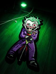 an image of a creepy clown on the floor with green light in the dark room