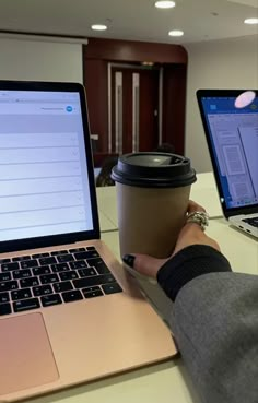 two laptops and a coffee cup sitting on a table in front of each other