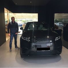 a man standing next to a black car in a showroom