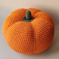 an orange knitted pumpkin sitting on top of a white table