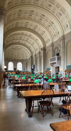 the inside of a library with tables and chairs, bookshelves and green umbrellas