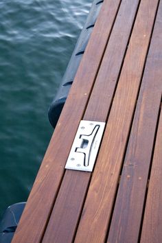 a wooden dock next to the water with a metal object on it's end