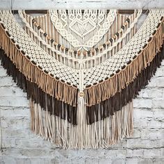 a wall hanging made out of macrame and leather fringes on a brick wall