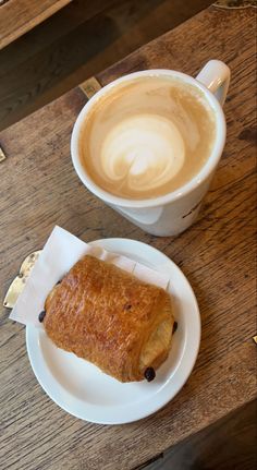 there is a pastry on the plate and a cup of coffee in the back ground