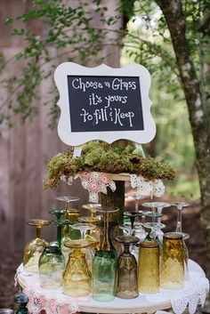 a table topped with lots of jars filled with liquid next to a sign that says choose a glass it's going to fill up