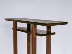 a wooden table with two shelves on each side and a white wall in the background