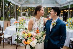 a man and woman standing next to each other in front of a table with flowers