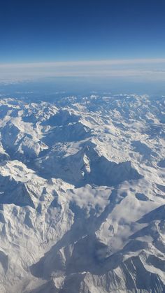 the view from an airplane looking down on snow covered mountains