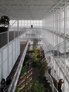 people are walking around in the atrium of an office building with glass walls and metal railings