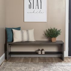 a wooden bench sitting in front of a door with shoes on it and a plant next to it