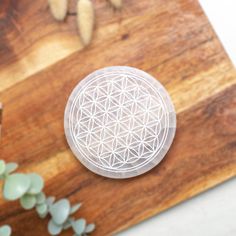 a wooden cutting board topped with a flower of life design