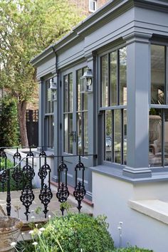 a building with many windows and iron railings on the side walk near some bushes