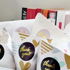 several thank you bags with gold foil lettering and hearts on them are sitting in front of bookshelves