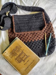 a crocheted purse sitting on top of a bed next to an old book