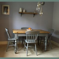 a dining room table with chairs and a bowl of oranges on top of it