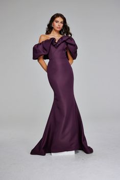 a woman in a purple gown posing for the camera with her hands on her hips