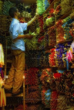 a man standing on a ladder in front of a store filled with lots of bracelets