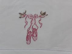 a pair of ballet shoes embroidered onto a white cloth