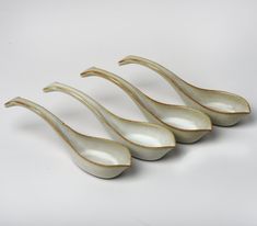 three white bowls with curved handles are shown