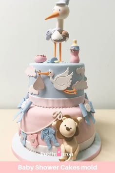 a baby shower cake with a stork, teddy bear and other items on top