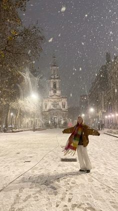 a man standing in the snow with his arms spread out to catch some air while it is snowing