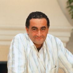 a man sitting at a table in front of a potted plant