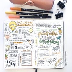 an open planner with pens and pencils next to it