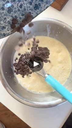 a bowl filled with batter and chocolate chips on top of a counter next to a spatula